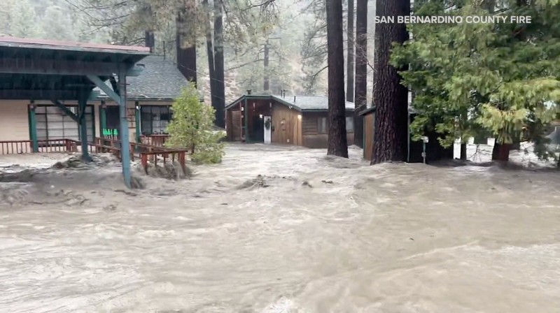 People sit on the roof of a building while they are stranded during floods partially submerging the surrounding area in the aftermath of torrential rains, in San Bernardino County, California, U.S. December 24, 2025 in this screengrab obtained from a social media video. Timothy and the Machine Music via Facebook/via REUTERS  THIS IMAGE HAS BEEN SUPPLIED BY A THIRD PARTY. MANDATORY CREDIT. NO RESALES. NO ARCHIVES.  Verification: Road layout, buildings and utility poles matched file and satellite images Date verified by original file metadata