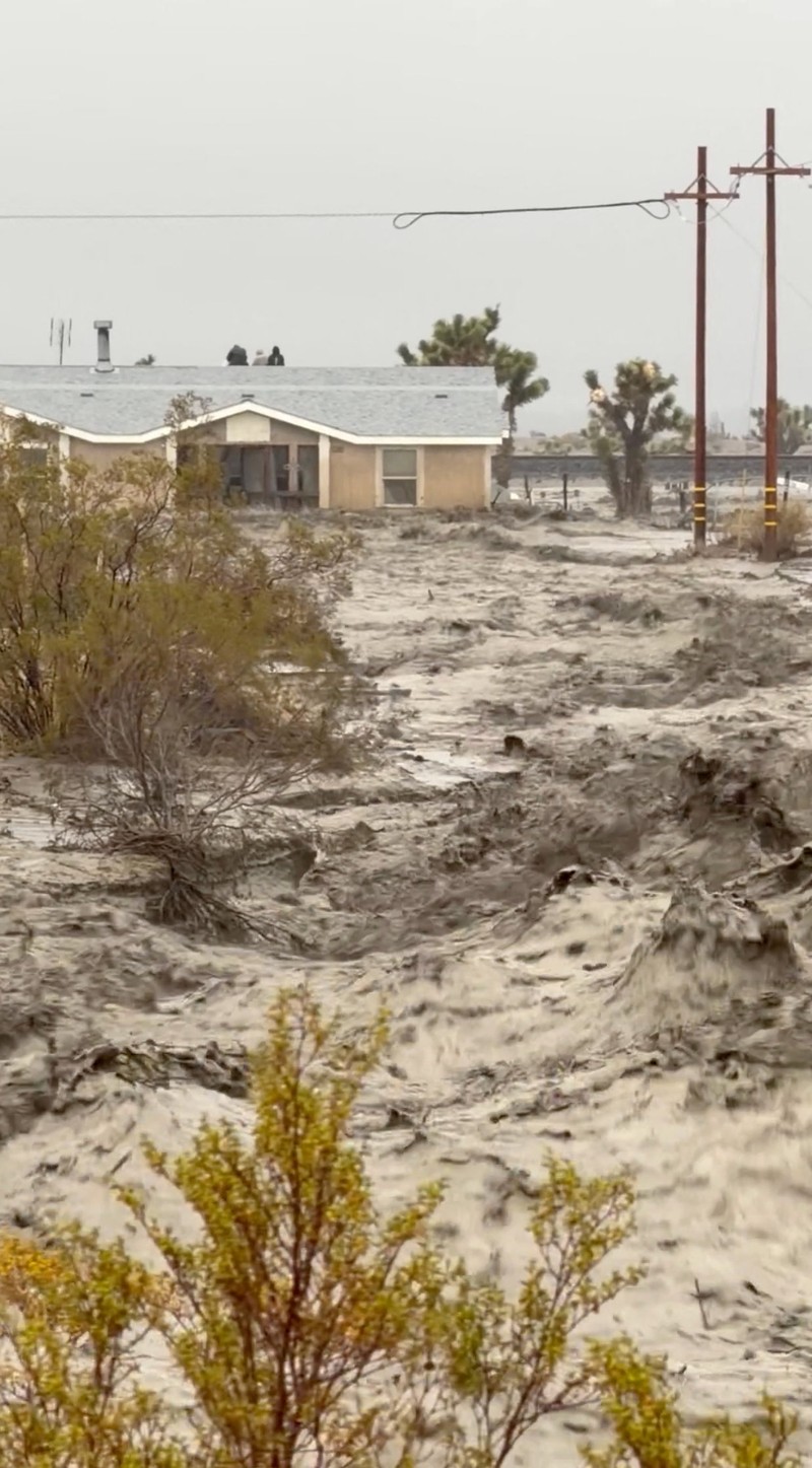People sit on the roof of a building while they are stranded during floods partially submerging the surrounding area in the aftermath of torrential rains, in San Bernardino County, California, U.S. December 24, 2025 in this screengrab obtained from a social media video. Timothy and the Machine Music via Facebook/via REUTERS  THIS IMAGE HAS BEEN SUPPLIED BY A THIRD PARTY. MANDATORY CREDIT. NO RESALES. NO ARCHIVES.  Verification: Road layout, buildings and utility poles matched file and satellite images Date verified by original file metadata