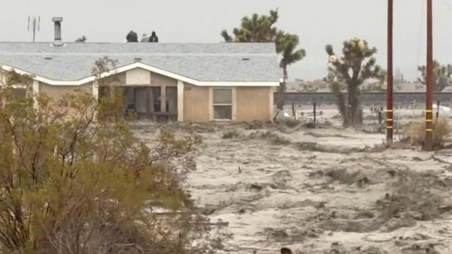 People sit on the roof of a building while they are stranded during floods partially submerging the surrounding area in the aftermath of torrential rains, in San Bernardino County, California, U.S. December 24, 2025 in this screengrab obtained from a social media video. Timothy and the Machine Music via Facebook/via REUTERS  THIS IMAGE HAS BEEN SUPPLIED BY A THIRD PARTY. MANDATORY CREDIT. NO RESALES. NO ARCHIVES.  Verification: Road layout, buildings and utility poles matched file and satellite images Date verified by original file metadata