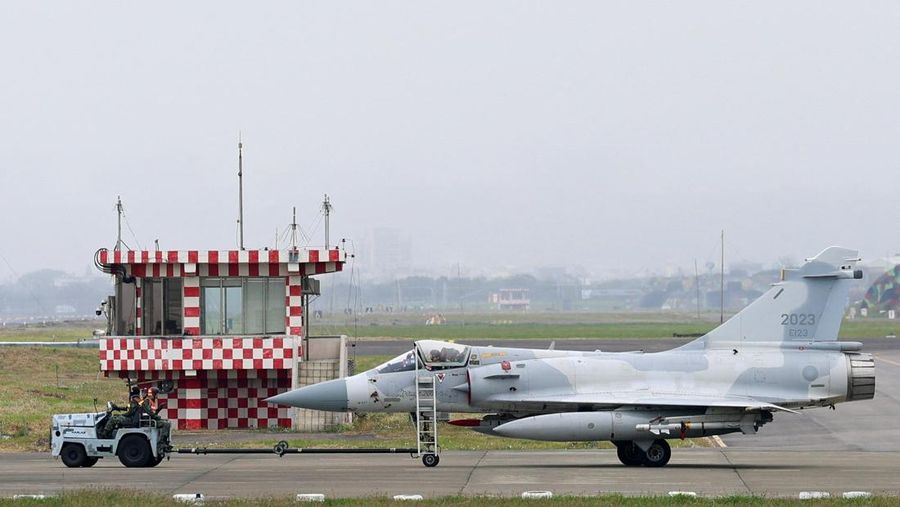 A person takes a photo of a flight information display screen that shows cancelled flights at the Taipei Songshan Airport, as China conducts 