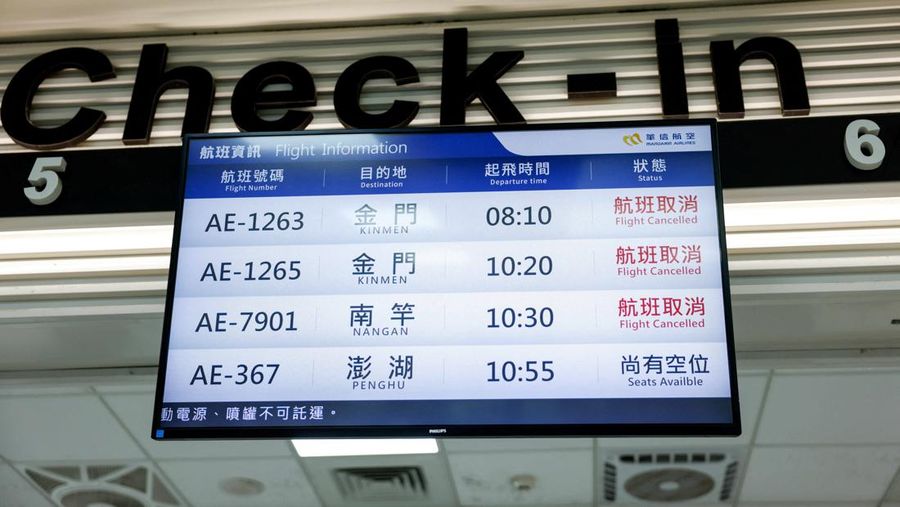 A person takes a photo of a flight information display screen that shows cancelled flights at the Taipei Songshan Airport, as China conducts 