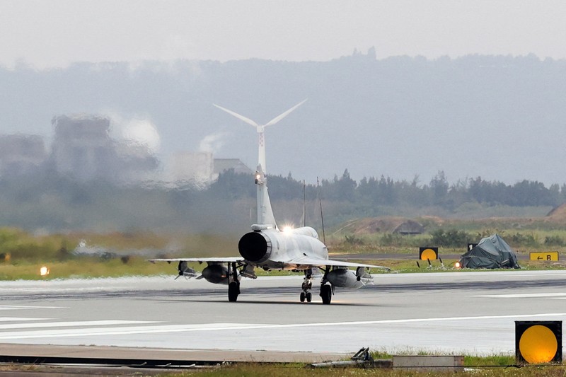 A person takes a photo of a flight information display screen that shows cancelled flights at the Taipei Songshan Airport, as China conducts