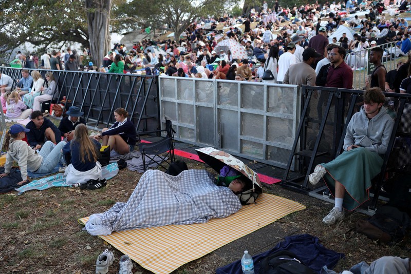Orang-orang berkumpul di Circular Quay dekat Gedung Opera Sydney menjelang pertunjukan kembang api Malam Tahun Baru, di Sydney, Australia, 31 Desember 2025. (REUTERS/Hollie Adams)