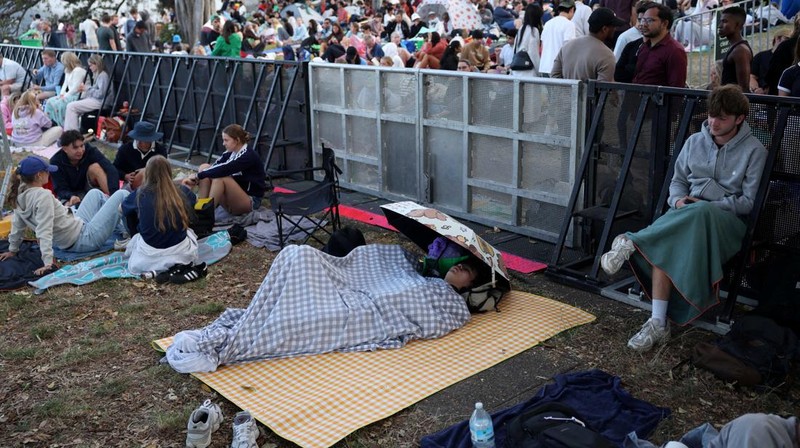Orang-orang berkumpul di Circular Quay dekat Gedung Opera Sydney menjelang pertunjukan kembang api Malam Tahun Baru, di Sydney, Australia, 31 Desember 2025. (REUTERS/Hollie Adams)