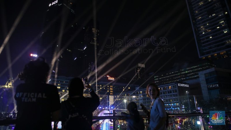 Warga menyaksikan atraksi formasi drone saat Perayaan Tahun Baru 2026 di Bundaran Hotel Indonesia (HI), Jakarta, Kamis (1/1/2026). (CNBC Indonesia/Faisal Rahman)