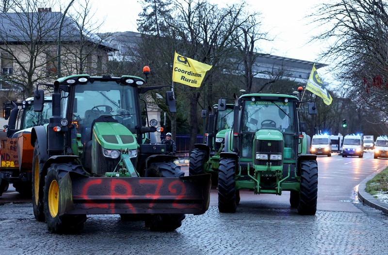 Orang-orang berjalan di samping traktor yang memblokir jalan di dekat Menara Eiffel, saat para petani Prancis memprotes penanganan pemerintah terhadap perjanjian perdagangan bebas Uni Eropa-Mercosur dan penanganan wabah penyakit kulit berbenjol, di Paris, Prancis, 8 Januari 2026. (REUTERS/Gonzalo Fuentes)