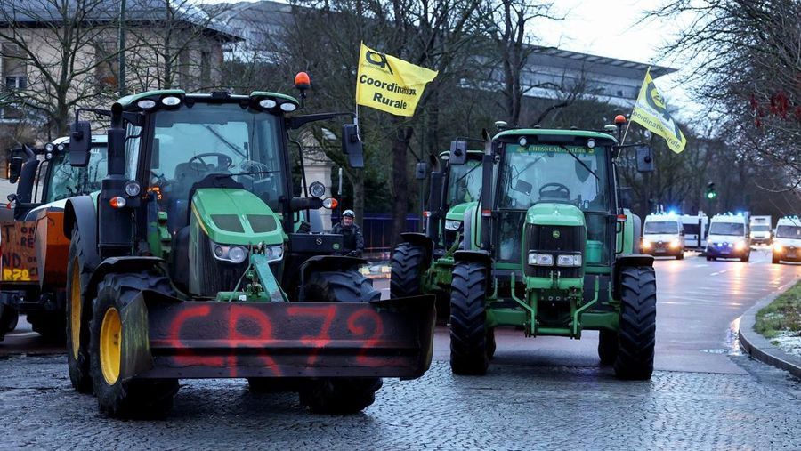 Orang-orang berjalan di samping traktor yang memblokir jalan di dekat Menara Eiffel, saat para petani Prancis memprotes penanganan pemerintah terhadap perjanjian perdagangan bebas Uni Eropa-Mercosur dan penanganan wabah penyakit kulit berbenjol, di Paris, Prancis, 8 Januari 2026. (REUTERS/Gonzalo Fuentes)