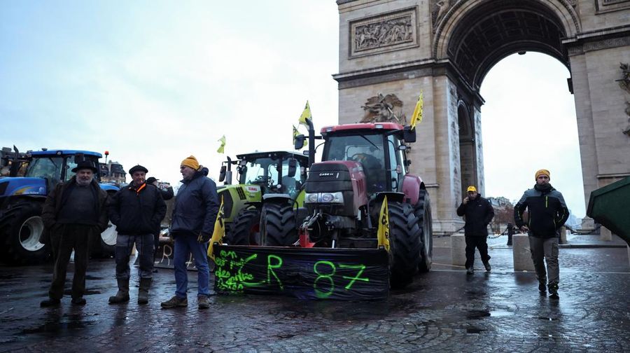 Orang-orang berjalan di samping traktor yang memblokir jalan di dekat Menara Eiffel, saat para petani Prancis memprotes penanganan pemerintah terhadap perjanjian perdagangan bebas Uni Eropa-Mercosur dan penanganan wabah penyakit kulit berbenjol, di Paris, Prancis, 8 Januari 2026. (REUTERS/Gonzalo Fuentes)