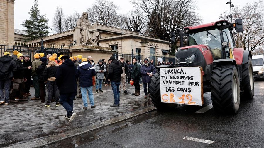 Orang-orang berjalan di samping traktor yang memblokir jalan di dekat Menara Eiffel, saat para petani Prancis memprotes penanganan pemerintah terhadap perjanjian perdagangan bebas Uni Eropa-Mercosur dan penanganan wabah penyakit kulit berbenjol, di Paris, Prancis, 8 Januari 2026. (REUTERS/Gonzalo Fuentes)