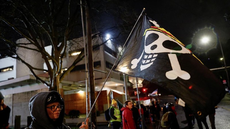 Seorang demonstran mengibarkan bendera Jolly Roger Bajak Laut Topi Jerami dari serial 