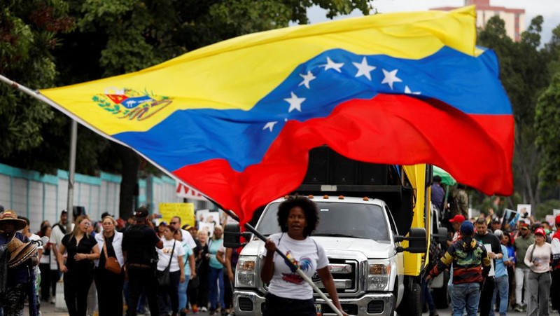 Ribuan warga berkumpul di berbagai wilayah Caracas sambil melambaikan bendera nasional dan memegang foto pasangan itu, menyerukan agar Maduro dan Flores dibebaskan dari tahanan. Aksi massa ini berlangsung di tengah ketegangan politik dan gejolak yang terus bergulir di negara tersebut. (REUTERS/Fausto Torrealba)