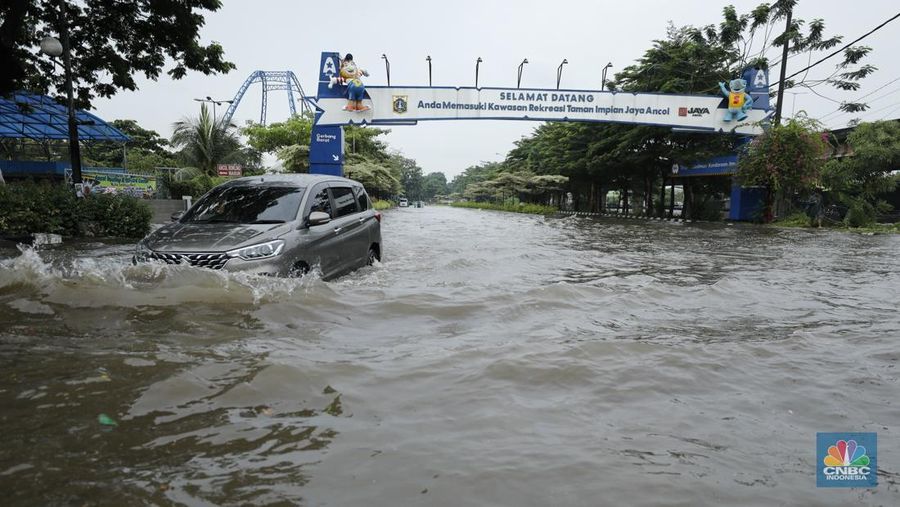 Pengendara sepeda motor melewati banjir di depan pintu masuk Taman Impian Jaya Ancol (pintu barat)di Pademangan, Jakarta, Senin (12/1/2026). (CNBC Indonesia/Tri Susilo)