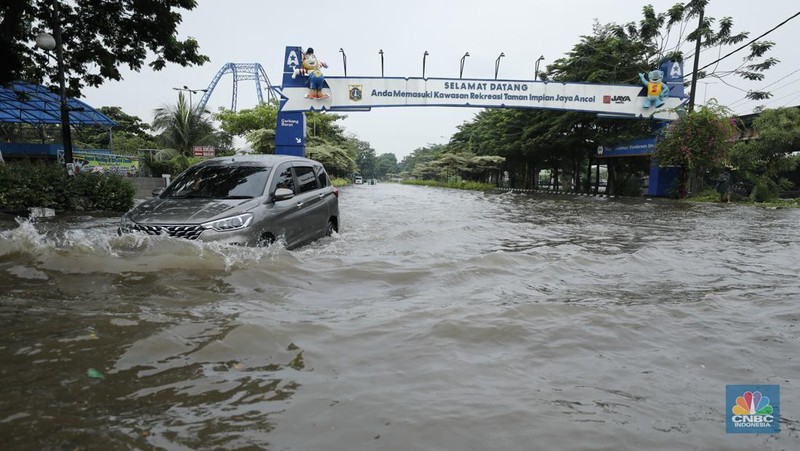 Pengendara sepeda motor melewati banjir di depan pintu masuk Taman Impian Jaya Ancol (pintu barat)di Pademangan, Jakarta, Senin (12/1/2026). (CNBC Indonesia/Tri Susilo)