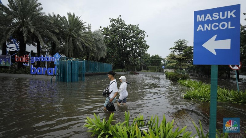 Pengendara sepeda motor melewati banjir di depan pintu masuk Taman Impian Jaya Ancol (pintu barat)di Pademangan, Jakarta, Senin (12/1/2026). (CNBC Indonesia/Tri Susilo)