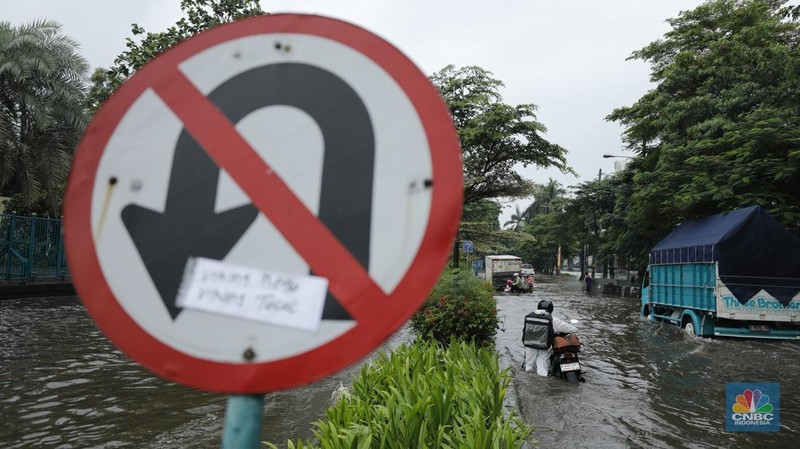 Pengendara sepeda motor melewati banjir di depan pintu masuk Taman Impian Jaya Ancol (pintu barat)di Pademangan, Jakarta, Senin (12/1/2026). (CNBC Indonesia/Tri Susilo)