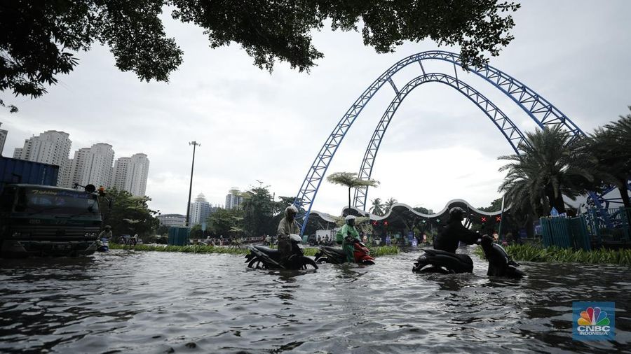 Pengendara sepeda motor melewati banjir di depan pintu masuk Taman Impian Jaya Ancol (pintu barat)di Pademangan, Jakarta, Senin (12/1/2026). (CNBC Indonesia/Tri Susilo)