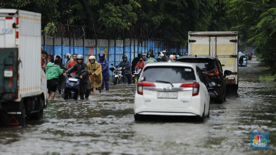 Pengendara sepeda motor melewati banjir di depan pintu masuk Taman Impian Jaya Ancol (pintu barat)di Pademangan, Jakarta, Senin (12/1/2026). (CNBC Indonesia/Tri Susilo)