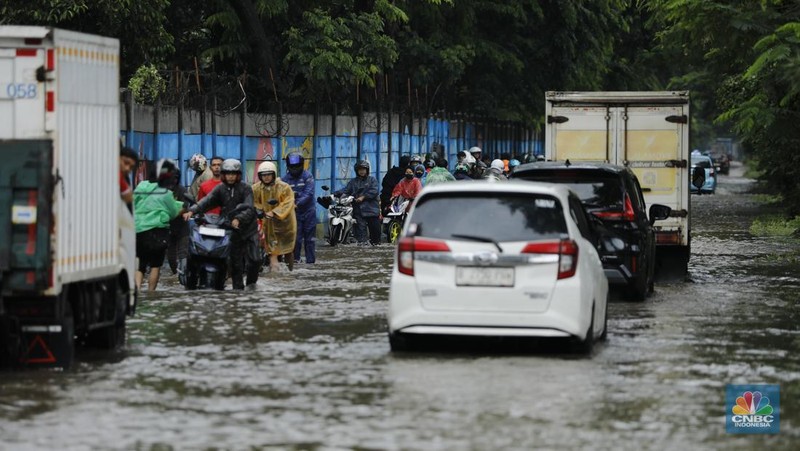 Pengendara sepeda motor melewati banjir di depan pintu masuk Taman Impian Jaya Ancol (pintu barat)di Pademangan, Jakarta, Senin (12/1/2026). (CNBC Indonesia/Tri Susilo)