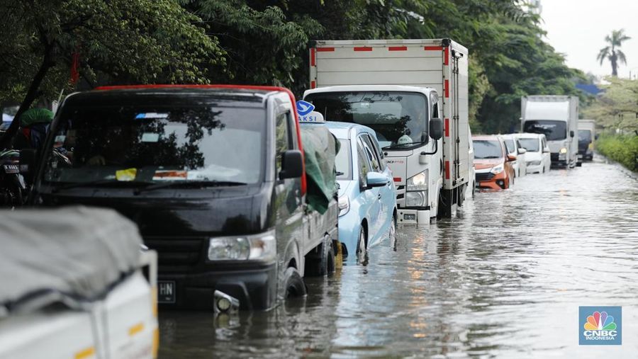 Pengendara sepeda motor melewati banjir di depan pintu masuk Taman Impian Jaya Ancol (pintu barat)di Pademangan, Jakarta, Senin (12/1/2026). (CNBC Indonesia/Tri Susilo)