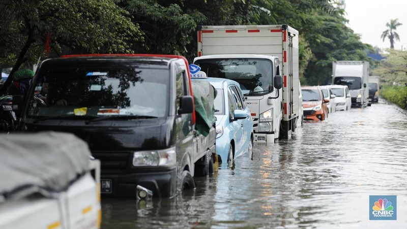 Pengendara sepeda motor melewati banjir di depan pintu masuk Taman Impian Jaya Ancol (pintu barat)di Pademangan, Jakarta, Senin (12/1/2026). (CNBC Indonesia/Tri Susilo)