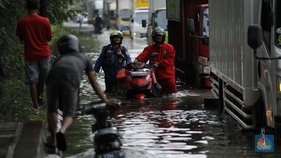 Pengendara sepeda motor melewati banjir di depan pintu masuk Taman Impian Jaya Ancol (pintu barat)di Pademangan, Jakarta, Senin (12/1/2026). (CNBC Indonesia/Tri Susilo)