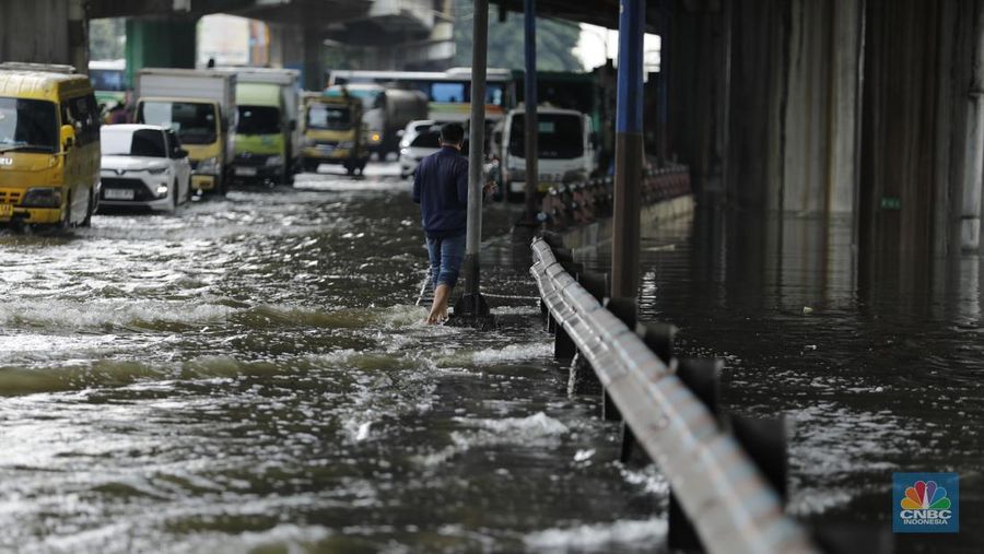 Pengendara sepeda motor melewati banjir di depan pintu masuk Taman Impian Jaya Ancol (pintu barat)di Pademangan, Jakarta, Senin (12/1/2026). (CNBC Indonesia/Tri Susilo)