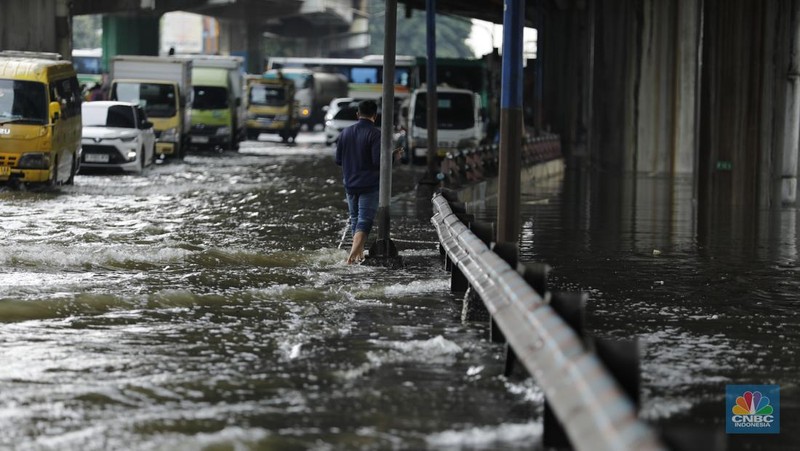 Pengendara sepeda motor melewati banjir di depan pintu masuk Taman Impian Jaya Ancol (pintu barat)di Pademangan, Jakarta, Senin (12/1/2026). (CNBC Indonesia/Tri Susilo)