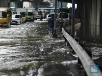 Pengendara sepeda motor melewati banjir di depan pintu masuk Taman Impian Jaya Ancol (pintu barat)di Pademangan, Jakarta, Senin (12/1/2026). (CNBC Indonesia/Tri Susilo)