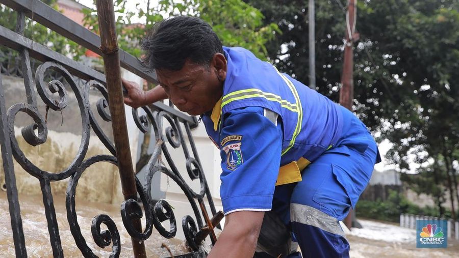 Petugas Sumber Daya Air (SDA) tampak mengangkat tumpukan sampah yang tersangkut di aliran Kali Krukut, kawasan Perumahan Puri Mutiara, Cilandak, Jakarta Selatan, Senin (12/1/2026). (CNBC Indonesia/Muhammad Sabki)