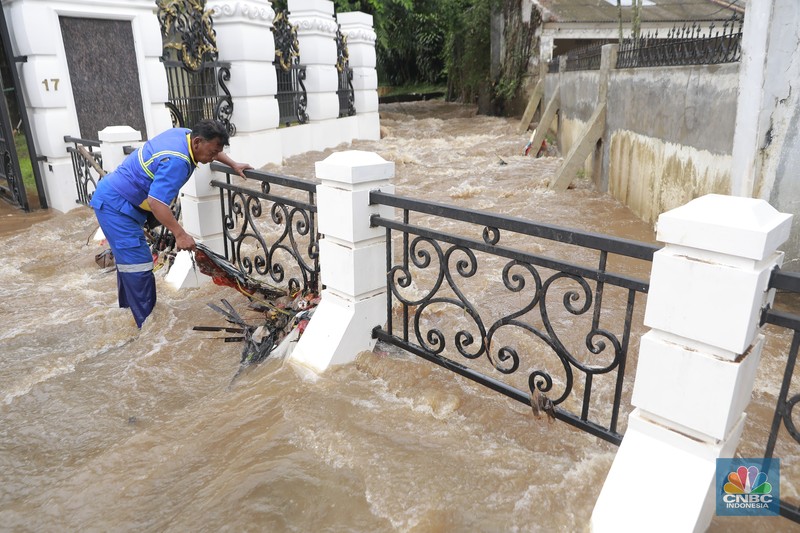 Petugas Sumber Daya Air (SDA) tampak mengangkat tumpukan sampah yang tersangkut di aliran Kali Krukut, kawasan Perumahan Puri Mutiara, Cilandak, Jakarta Selatan, Senin (12/1/2026). (CNBC Indonesia/Muhammad Sabki)