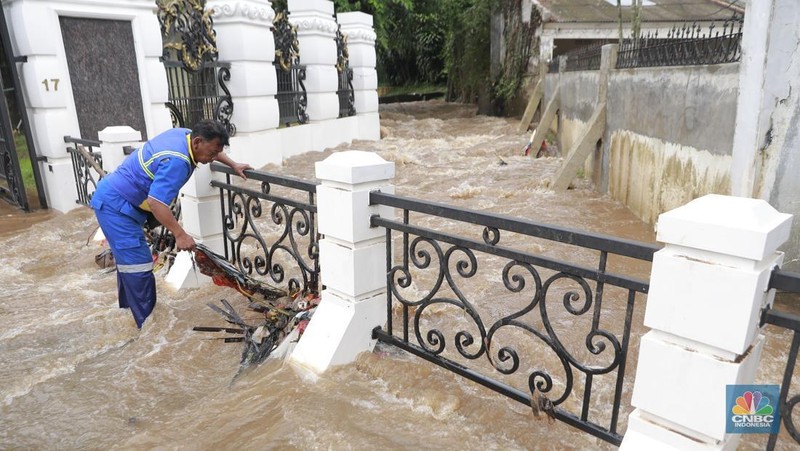 Petugas Sumber Daya Air (SDA) tampak mengangkat tumpukan sampah yang tersangkut di aliran Kali Krukut, kawasan Perumahan Puri Mutiara, Cilandak, Jakarta Selatan, Senin (12/1/2026). (CNBC Indonesia/Muhammad Sabki)
