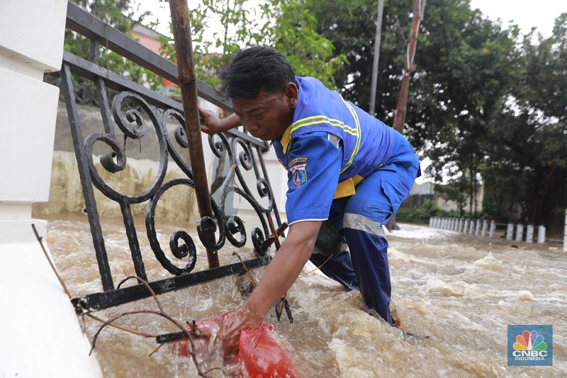 Petugas Sumber Daya Air (SDA) tampak mengangkat tumpukan sampah yang tersangkut di aliran Kali Krukut, kawasan Perumahan Puri Mutiara, Cilandak, Jakarta Selatan, Senin (12/1/2026). (CNBC Indonesia/Muhammad Sabki)