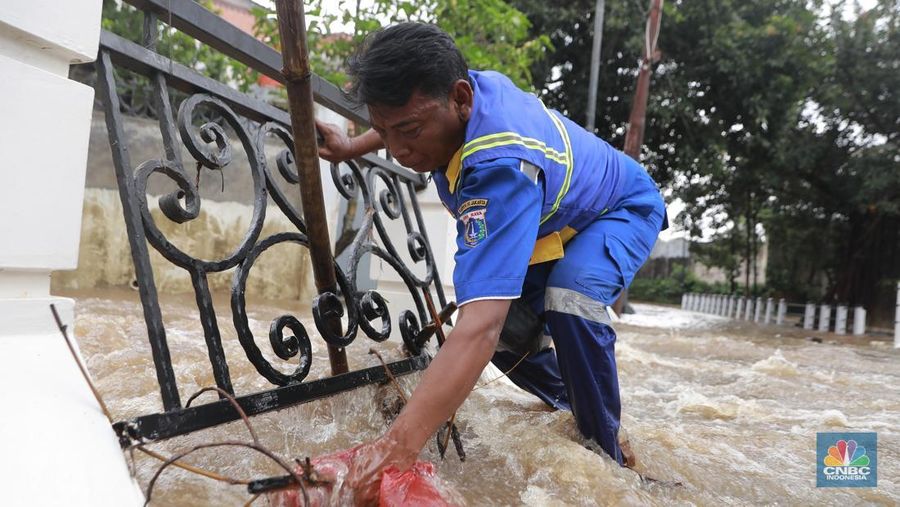Petugas Sumber Daya Air (SDA) tampak mengangkat tumpukan sampah yang tersangkut di aliran Kali Krukut, kawasan Perumahan Puri Mutiara, Cilandak, Jakarta Selatan, Senin (12/1/2026). (CNBC Indonesia/Muhammad Sabki)