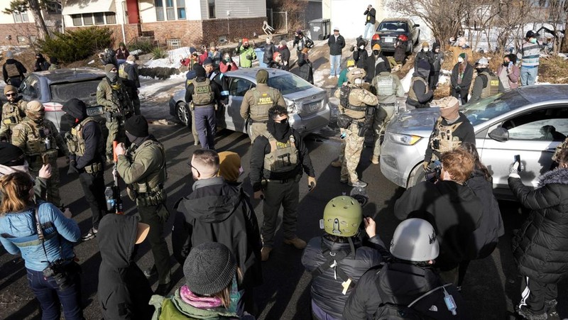 Agen Imigrasi dan Bea Cukai AS (ICE) berdiri di samping mobil warga sipil yang rusak akibat ditabrak oleh ICE, setelah seorang agen ICE menembak mati Renee Nicole Good, di Minneapolis, Minnesota, AS, 12 Januari 2026. (REUTERS/Tim Evans)