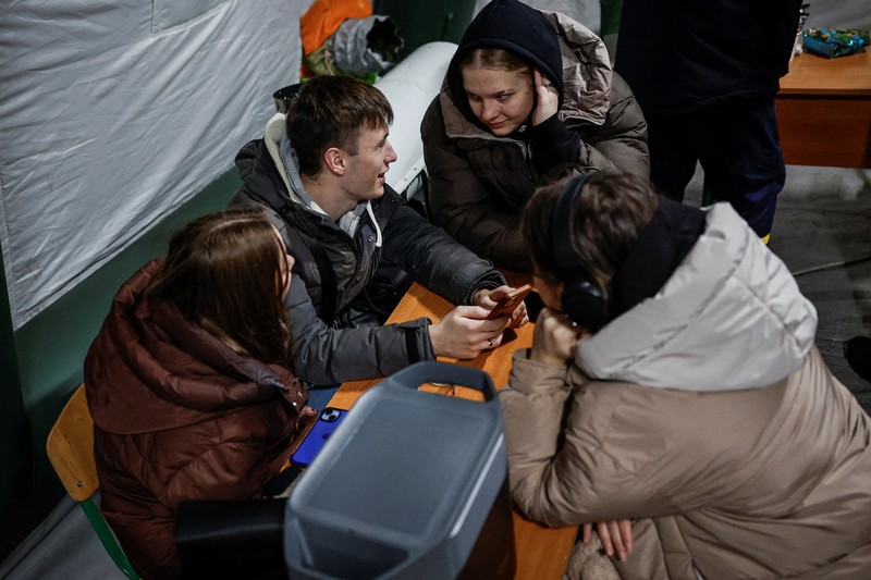 Seseorang berdiri di luar pusat Point of Invincibility, tempat perlindungan yang dikelola pemerintah yang menawarkan layanan dasar dan penghangat selama pemadaman listrik, di mana warga menghangatkan diri dan mengisi daya perangkat mereka, selama pemadaman listrik setelah infrastruktur sipil penting dihantam oleh serangan rudal dan drone Rusia baru-baru ini, di tengah serangan Rusia terhadap Ukraina, di Kyiv, Ukraina, 12 Januari 2026. (REUTERS/Alina Smutko)