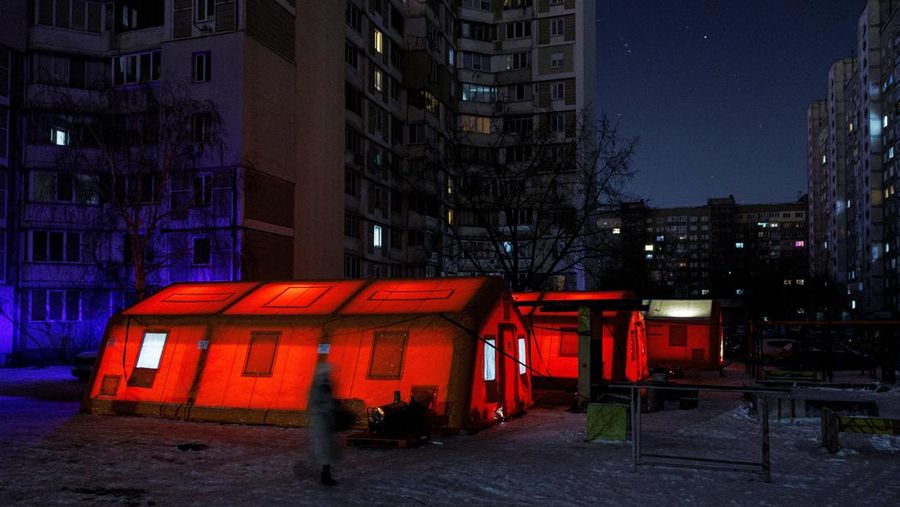 Seseorang berdiri di luar pusat Point of Invincibility, tempat perlindungan yang dikelola pemerintah yang menawarkan layanan dasar dan penghangat selama pemadaman listrik, di mana warga menghangatkan diri dan mengisi daya perangkat mereka, selama pemadaman listrik setelah infrastruktur sipil penting dihantam oleh serangan rudal dan drone Rusia baru-baru ini, di tengah serangan Rusia terhadap Ukraina, di Kyiv, Ukraina, 12 Januari 2026. (REUTERS/Alina Smutko)