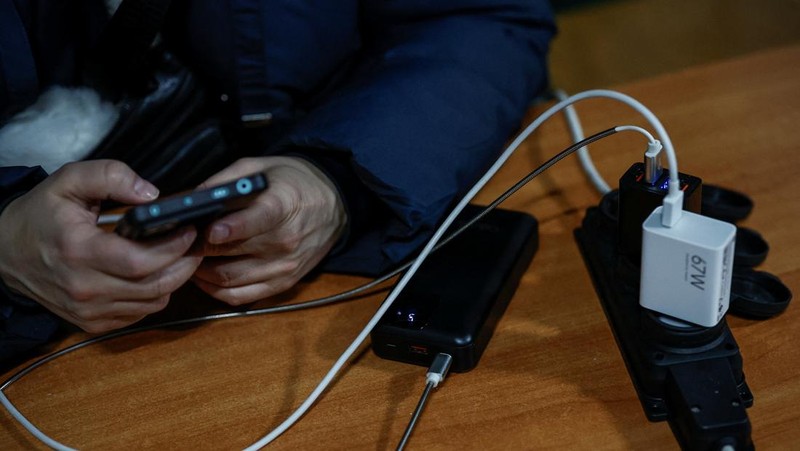 Seseorang berdiri di luar pusat Point of Invincibility, tempat perlindungan yang dikelola pemerintah yang menawarkan layanan dasar dan penghangat selama pemadaman listrik, di mana warga menghangatkan diri dan mengisi daya perangkat mereka, selama pemadaman listrik setelah infrastruktur sipil penting dihantam oleh serangan rudal dan drone Rusia baru-baru ini, di tengah serangan Rusia terhadap Ukraina, di Kyiv, Ukraina, 12 Januari 2026. (REUTERS/Alina Smutko)