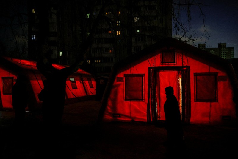Seseorang berdiri di luar pusat Point of Invincibility, tempat perlindungan yang dikelola pemerintah yang menawarkan layanan dasar dan penghangat selama pemadaman listrik, di mana warga menghangatkan diri dan mengisi daya perangkat mereka, selama pemadaman listrik setelah infrastruktur sipil penting dihantam oleh serangan rudal dan drone Rusia baru-baru ini, di tengah serangan Rusia terhadap Ukraina, di Kyiv, Ukraina, 12 Januari 2026. (REUTERS/Alina Smutko)