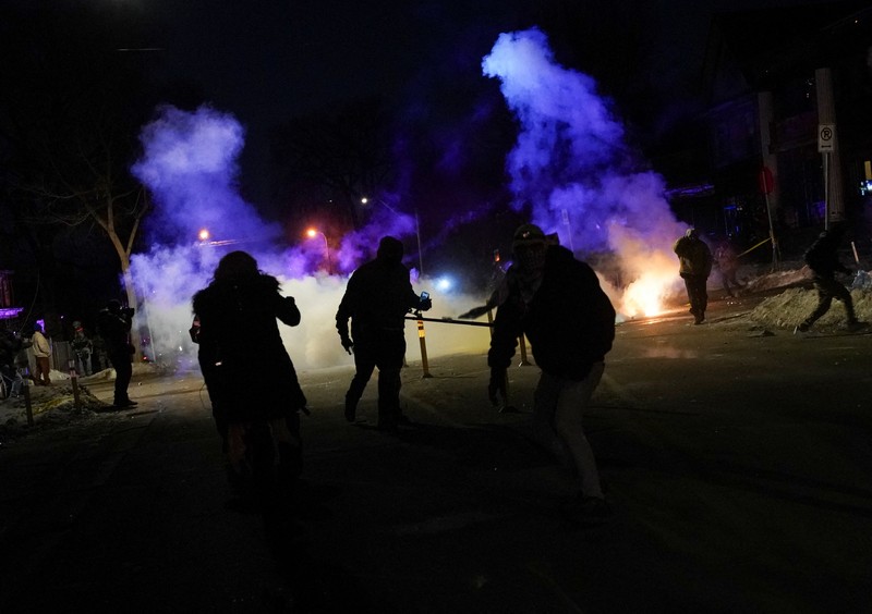 Para pengunjuk rasa berhadapan dan bentrok dengan pihak berwenang di Minneapolis utara dekat lokasi seorang pria ditembak di kaki pada Rabu (14/2/2026). (REUTERS/Ryan Murphy)