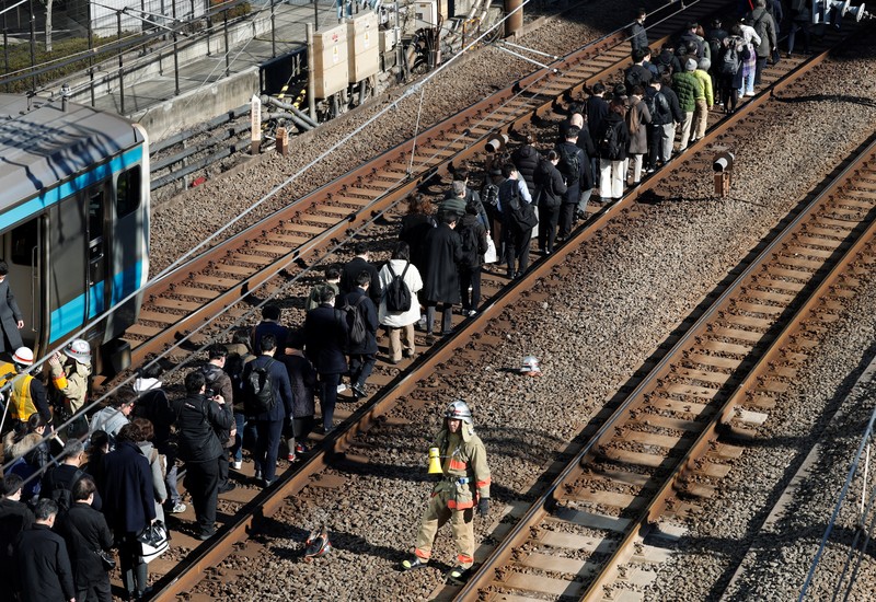 Penumpang dievakuasi dari kereta yang terhenti di jalur Keihin-Tohoku menuju stasiun Tamachi di Tokyo, Jepang, Jumat (16/1/2026). (REUTERS/Kim Kyung-Hoon)