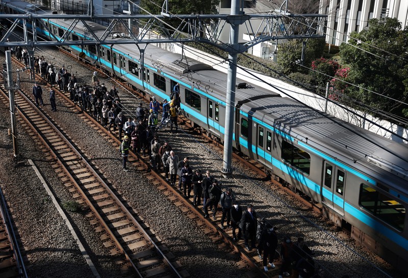 Penumpang dievakuasi dari kereta yang terhenti di jalur Keihin-Tohoku menuju stasiun Tamachi di Tokyo, Jepang, Jumat (16/1/2026). (REUTERS/Kim Kyung-Hoon)