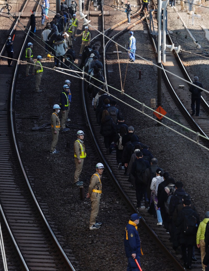 Penumpang dievakuasi dari kereta yang terhenti di jalur Keihin-Tohoku menuju stasiun Tamachi di Tokyo, Jepang, Jumat (16/1/2026). (REUTERS/Kim Kyung-Hoon)