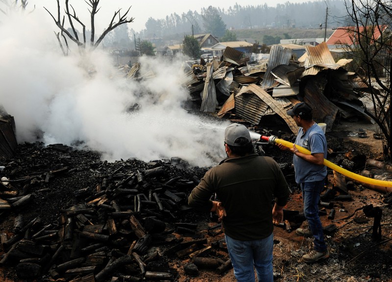 Sebuah tugu peringatan menandai lokasi di mana seseorang meninggal di masa lalu, di tengah tanah hangus setelah kebakaran hutan menghancurkan ratusan rumah, menewaskan beberapa orang dan memaksa evakuasi massal, sementara pihak berwenang terus berjuang melawan hampir dua lusin kobaran api yang diperparah oleh panas ekstrem dan angin kencang, di jalan antara Lirquen dan Punta de Parra, Chili, 19 Januari 2026. (REUTERS/Jose Luis Saavedra)