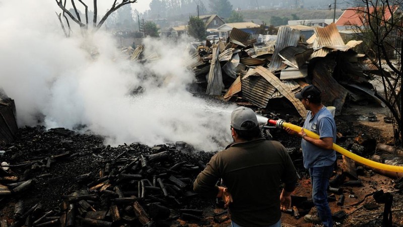 Sebuah tugu peringatan menandai lokasi di mana seseorang meninggal di masa lalu, di tengah tanah hangus setelah kebakaran hutan menghancurkan ratusan rumah, menewaskan beberapa orang dan memaksa evakuasi massal, sementara pihak berwenang terus berjuang melawan hampir dua lusin kobaran api yang diperparah oleh panas ekstrem dan angin kencang, di jalan antara Lirquen dan Punta de Parra, Chili, 19 Januari 2026. (REUTERS/Jose Luis Saavedra)