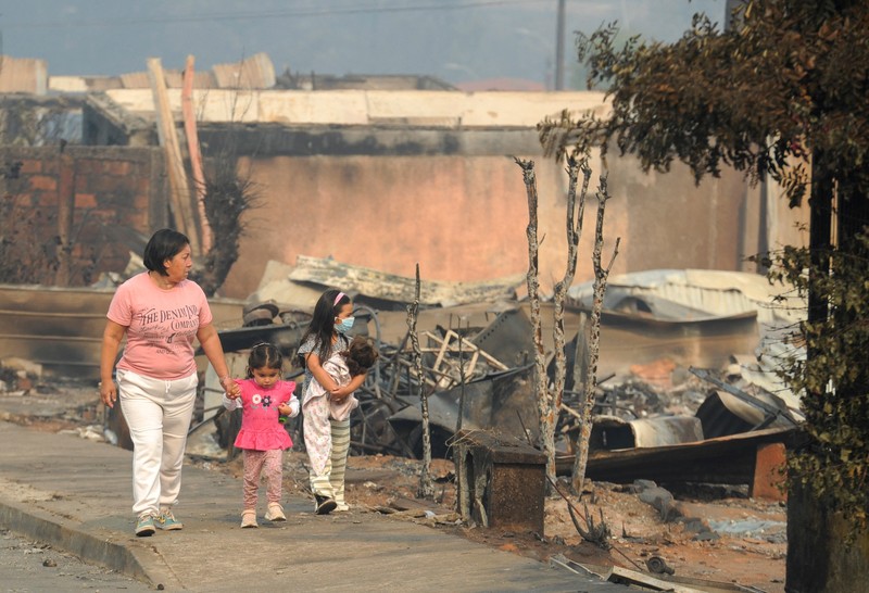 Sebuah tugu peringatan menandai lokasi di mana seseorang meninggal di masa lalu, di tengah tanah hangus setelah kebakaran hutan menghancurkan ratusan rumah, menewaskan beberapa orang dan memaksa evakuasi massal, sementara pihak berwenang terus berjuang melawan hampir dua lusin kobaran api yang diperparah oleh panas ekstrem dan angin kencang, di jalan antara Lirquen dan Punta de Parra, Chili, 19 Januari 2026. (REUTERS/Jose Luis Saavedra)