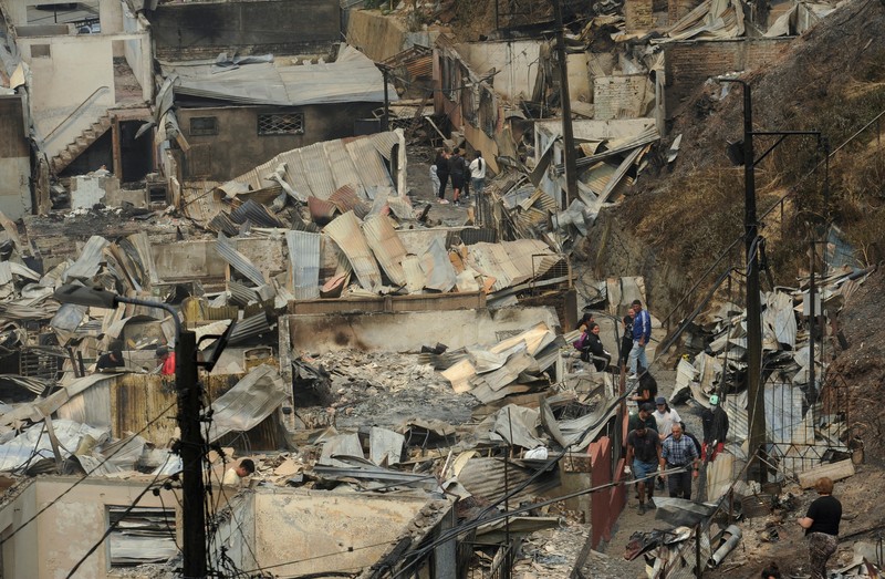 Sebuah tugu peringatan menandai lokasi di mana seseorang meninggal di masa lalu, di tengah tanah hangus setelah kebakaran hutan menghancurkan ratusan rumah, menewaskan beberapa orang dan memaksa evakuasi massal, sementara pihak berwenang terus berjuang melawan hampir dua lusin kobaran api yang diperparah oleh panas ekstrem dan angin kencang, di jalan antara Lirquen dan Punta de Parra, Chili, 19 Januari 2026. (REUTERS/Jose Luis Saavedra)