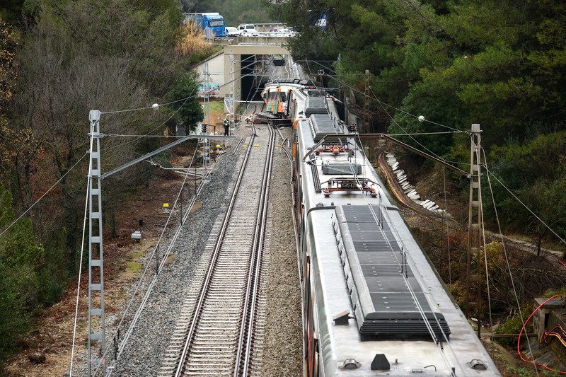 Polisi dan petugas pemadam kebakaran memeriksa lokasi kecelakaan kereta komuter, setelah dinding pembatas ambruk ke rel akibat hujan lebat, menewaskan masinis dan melukai beberapa orang, di Gelida, dekat Barcelona, ​​Spanyol, 21 Januari 2026. (REUTERS/Albert Gea)