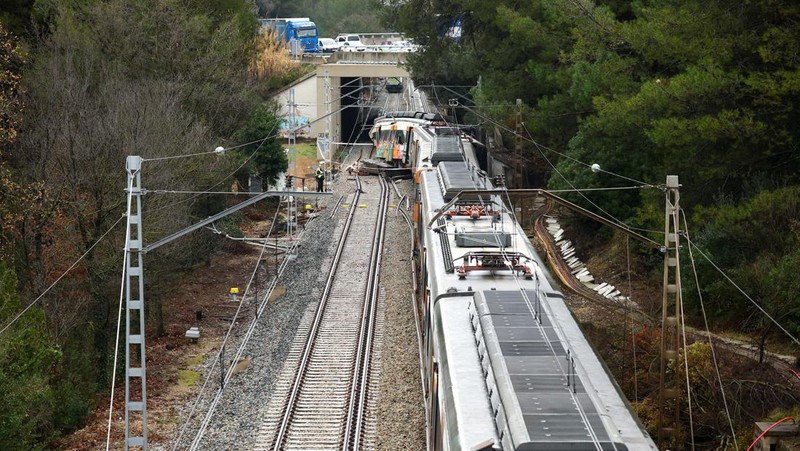 Polisi dan petugas pemadam kebakaran memeriksa lokasi kecelakaan kereta komuter, setelah dinding pembatas ambruk ke rel akibat hujan lebat, menewaskan masinis dan melukai beberapa orang, di Gelida, dekat Barcelona, ​​Spanyol, 21 Januari 2026. (REUTERS/Albert Gea)