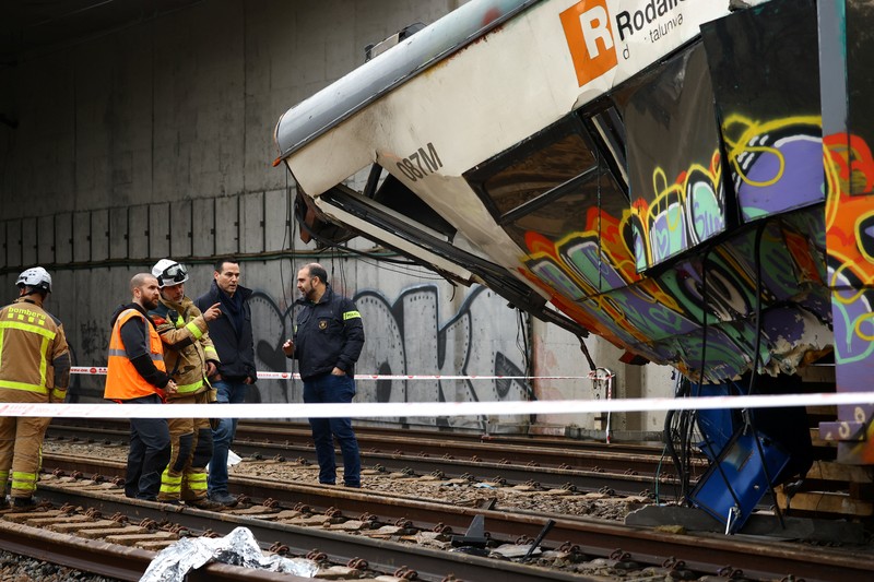 Polisi dan petugas pemadam kebakaran memeriksa lokasi kecelakaan kereta komuter, setelah dinding pembatas ambruk ke rel akibat hujan lebat, menewaskan masinis dan melukai beberapa orang, di Gelida, dekat Barcelona, ​​Spanyol, 21 Januari 2026. (REUTERS/Albert Gea)