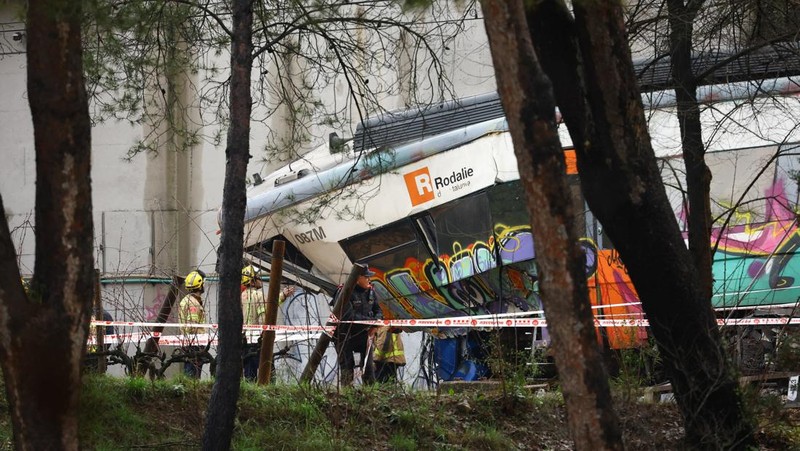 Polisi dan petugas pemadam kebakaran memeriksa lokasi kecelakaan kereta komuter, setelah dinding pembatas ambruk ke rel akibat hujan lebat, menewaskan masinis dan melukai beberapa orang, di Gelida, dekat Barcelona, ​​Spanyol, 21 Januari 2026. (REUTERS/Albert Gea)